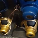 Fotografie zachycuje čtyři reproduktory umístěné uvnitř černé skříně. Dva horní reproduktory mají modré kovové magnetické systémy a dva spodní jsou v…