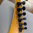 Fotografie zachycuje hlavu elektrické kytary z přírodního světlého dřeva s šesti černými ladicími kolíky. Na spodním kolíku je viditelný nápis GOTOH.…