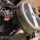 Detailní pohled na zadní část černého reproduktoru. Na stříbrném magnetu je bílá nálepka s modrým logem WHARFEDALE a nápisy PROFESSIONAL AUDIO COMPON…
