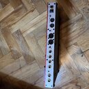 Zadní strana stříbrného elektronického zařízení s červeným okrajem. Jsou zde viditelné nápisy POWER, MIDI OUT(THRU), MIDI IN, BALANCED OUTPUT L a R,…