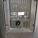 Detail zadní strany černého reproduktoru s plastovým krytem. Je zde vyraženo logo dB TECHNOLOGIES a nalepený štítek s nápisy „CAUTION TO PREVENT ELEC…