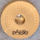 Zlatý kovový činel s kovaným povrchem v podobě drobných důlků. Na spodní části je černý nápis pAiste a pod ním menší text MADE IN SWITZERLAND. Povrch…