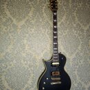 Černá elektrická kytara s tmavým hnedým hřidnicem a zlatým hardwarem. Na hlavě je viditelné logo "LTD". Tělo kytary má dva humbuckery, čtyři otočné k…