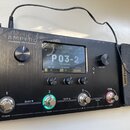 Černý efektový procesor s nápisem AMPERO Amp Modeler / Effects Processor. Zařízení má digitální displej, na kterém je zobrazen text P03-2 a další par…