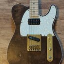 Elektrická kytara s hnědým dřevěným korpusem a bílým lemováním. Má bílo-perleťový pickguard, zlatý hardware a hmatník ze světlého dřeva. Na kobylce j…