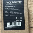 Fotografie znázorňuje kartonové balení s černým štítkem. Na štítku je uveden název ROCKPOWER by WARWICK a označení Power Supply NT 22. Jsou zde uvede…