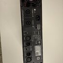 Zadní strana černého rackového zesilovače s dvěma chladicími ventilátory. Na šasi jsou nápisy CHANNEL A, CHANNEL B, CLASS 3 WIRING FOR BRIDGED OUTPUT…
