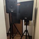 Dva černé reproduktory umístěné na černých tripodních stojanů. Na přední mřížce každého reproduktoru je umístěno malé logo s nápisem „Soundking“. Pov…
