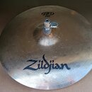 Kovový činel stříbrné barvy s viditelným rýhováním. Na povrchu je velký černý nápis Zildjian a v horní části logo ZBT s doplňujícím textem Hi-hat 14"…