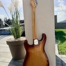 Zadní strana elektrické kytary s trupem v hnědém sunburst provedení a světle hnědým krkem. Na kovovém krytu hрифového spoje je vidět nápis Fender. Po…