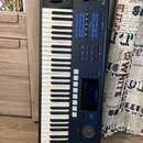 Tmavě modrý digitální klavír s bílými a černými klávesami. V pravém horním rohu je nápis PC3 LE 6 a v pravé části těla je viditelné logo KURZWEIL. Ná…