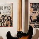 Zadní strana elektrické kytary s trupem v barevnosti sunburst a světlým dřevěným hnedlem. Na hlavě je viditelné logo Fender a nápis MADE IN USA. V mí…