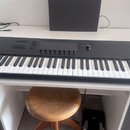 Černá klaviatura s bílými a černými klávesami umístěná na bílém stole. Na levé straně horního panelu je nápis KONTROL S61 MK. Panel obsahuje několik…