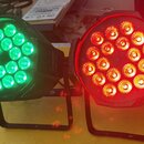 Dvě černé LED par světla s kovovými stojánky. Levý přístroj svítí zeleně a pravý červeně, oba mají v čele 12 kulatých LED diod. Na přístrojích nejsou…
