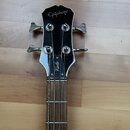 Fotografie zachycuje hmatník a hlavu basové kytary s černým lakem. Na hlavě je bílý nápis Epiphone a pod ním svisle orientovaný nápis Viola. Nástroj…