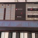 Detailní pohled na ovládací panel a klávesy elektronického klavíru. Na černém panelu jsou viditelné nápisy „Parameters“, „Global“ a „Sound / Setup Se…