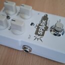 Bílý efekt pedál s pěti bílými oválnými knoflíky a jedním přepínačem. Na horní straně je nápis SPARK, tc electronic a označení vstupů OUT a IN. U kno…