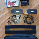 Sada příslušenství značky ROCKBOARD, která obsahuje černý napájecí blok s nápisem ISO Power Block V6 a přívodní adaptér. Součástí je černý kabel, pol…