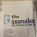 Hnědý papírový karton s viditelnými pomačkaninami a vrásky. Na povrchu je černý nápis „the sssnake“ s doprovodným logem a pod ním text „MC 8 Multicor…
