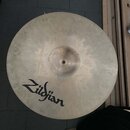 Kruhový činel z kovu s viditelným kování povrchu. Na spodní části je černý nápis Zildjian. Povrch vykazuje drobné nečistoty a známky používání.