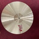 Kruhový mosazný činel s viditelným broušením povrchu. Na spodní části je červeně a černě vyvedený nápis PAISTE PXh a pod ním text 20" HEAVY RIDE. Pov…