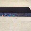 Černý rackový kompresor s modrými zdobnými liniemi na předním panelu. Na levé straně je bílý nápis dbx 160A a vpravo nápis COMPRESSOR/LIMITER. Zaříze…