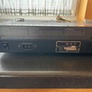 Zadní strana černého elektronického hudebního zařízení. Na štítku je uveden nápis Roland Corp. MADE IN JAPAN, napětí AC 220V ~ 50/60Hz a nečitelný k…