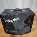 Černý textilní kryt na hudební zesilovač s rukojetí nahoře. Na přední straně je bílý nápis Fender®. Povrch materiálu vykazuje vrasky.