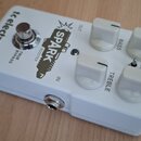 Bílý efekt pedál s nápisy tc electronic, SPARK a BOOSTER. Na horní straně jsou čtyři bílé oválné ovladače s popisky BASS, GAIN, TREBLE a LEVEL. Mezi…