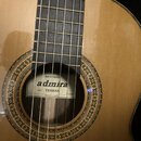 Kytara s přírodním dřevem a hnědým hmatníkem. U otvoru rezonanční skříně je štítek s nápisy ARTESANIA, admira, mod. TERESA a Fabricada en España. Kol…