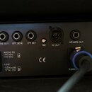 Zadní panel černého komba s řadou konektorů a ovládacích prvků. Jsou zde nápisy TUNER, LINE OUT, EFF.SEND, EFF.RET, PRE, DI OUT a SPEAKER OUT, dále p…