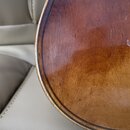Detailní záběr na hranu a povrch dřevěného nástroje v hnědé barvě s lakovaným povrchem. Na hraně je vidět tmavý dekorativní pruh (purpurin). Povrch v…