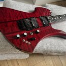 Červená elektrická kytara s výraznou plamenovou strukturou dřeva na topu. Na snímačích je viditelný nápis Duncan. Nástroj má dva humbuckery, jeden tó…