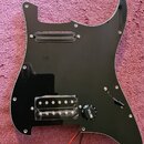 Černý plastový pickguard pro elektrickou kytaru s vyřezem na hmatník a ovládací prvky. Je vybaven jedním černým snímačem v horní části a jedním sníma…