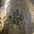 Detailní záběr na kovový činel s kladeným povrchem. Na povrchu je černý nápis TOP BIG BEAT HI-HAT 15". Povrch vykazuje drobné škrábance a známky použ…