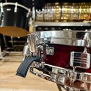 Detailní pohled na horní hranu tmavě červeného bubnu s chromovaným obručem a mechanismem. Na chromovaných částech nejsou žádné viditelné nápisy ani l…