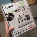 Kartonová krabice s produktovou fotografií mixovací konzole Yamaha AG03. Na krabici je v horní části logo YAMAHA a ve spodní části nápis AG03 doprová…