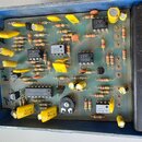 Fotografie zachycuje vnitřek modrého kovového šasi s elektronickou deskou plnou součástek. Na desce jsou viditelné integrované obvody s nápisy MN3007…
