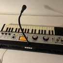 Černý syntetizátor s klaviaturou a ovládacím panelem. Na pravé straně je nápis KORG microKORG XL a na spodní hraně uprostřed logo KORG. Přístroj má v…