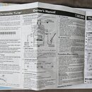 Fotografie zachycuje otevřený uživatelský manuál k chromatickému ladítku. Na stránkách je vidět text v angličtině a japonštině, schéma s popisem ovlá…