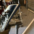 Detail hlavy elektrické kytary v černé barvě s bílým lemováním hran. Na povrchu je vidět bílý nápis Jackson a černé ladičky. Povrch vykazuje drobné š…