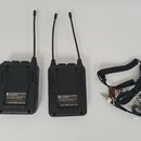 Dvě černé bezdrátové vysílače s anténami a přiloženým kabelem s mikrofonem. Na obou zařizeních je bílý štítek s nápisy: SAVE RECORDING WIRELESS MICRO…