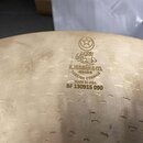 Detail vnitřní strany činely z mosazi s viditelným broušením povrchu. Na ploše je vyražen symbol hvězdy v kruhu, arabský nápis a text ZILDJIAN & CO.…