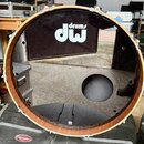 Kruhová basová blana s černým povrchem a vyřezaným otvorem v dolní části. Na horní polovině je bílé logo s nápisem drums dw. Blana je osazena dřevěný…