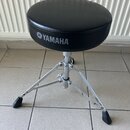 Černý polstrovaný hudební židliček s kovovým chromovaným stativem a gumovými koncovkami nohou. Na boku sedáku je bílý nápis YAMAHA s doprovodným loge…