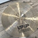 Zlatavý kovový činel s jemným broušeným povrchem. Na spodní straně je černý nápis UFIP Class Series EARCREATED CYMBALS. V horní části u středu jsou v…