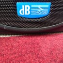 Detailní záběr na černý reproduktor s kovovou mřížkou. Na mřížce je umístěna modrá tabulka s bílým nápisem dB TECHNOLOGIES a grafickým symbolem vln.…