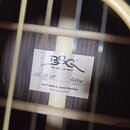 Detail vnitřku akustické kytary s bílou štítkovou nálepkou. Na nálepce je logo BSG a nápis the voice of wood. U políčka model je ručně zapsáno BA 27…