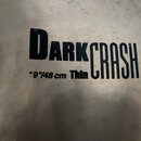 Detailní záběr na povrch kovového činele s viditelnou strukturou ražení. Na povrchu je černý nápis DARK CRASH a vedle něj menší text "19" / 48 cm Thi…