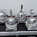 Šest kusů stříbrných kovových reflektorů umístěných v černém transportním kufru s hliníkovými hranami. Každý reflektor má v horní části úzkou kovovou…
